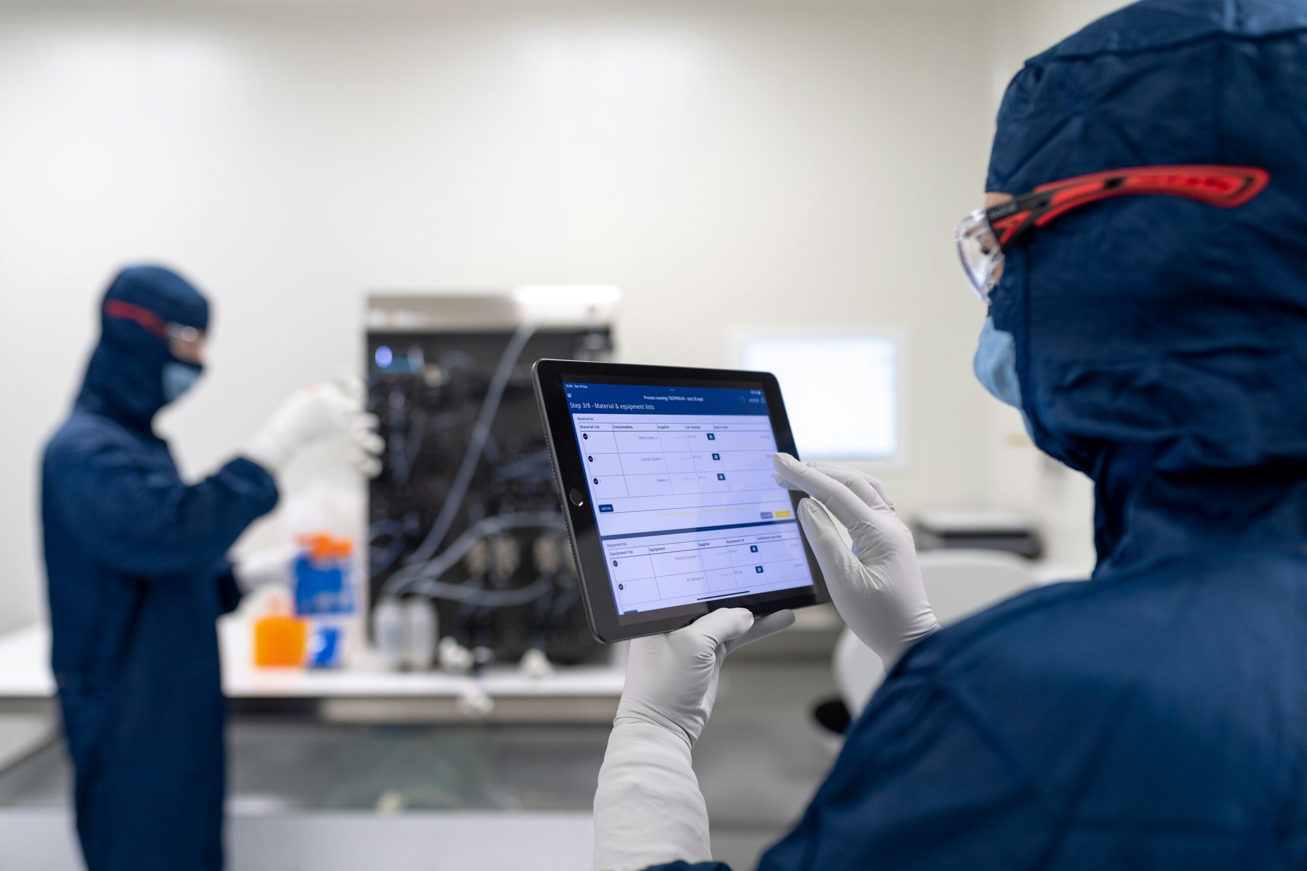 Two analysts in a cleanroom capturing results on a tablet